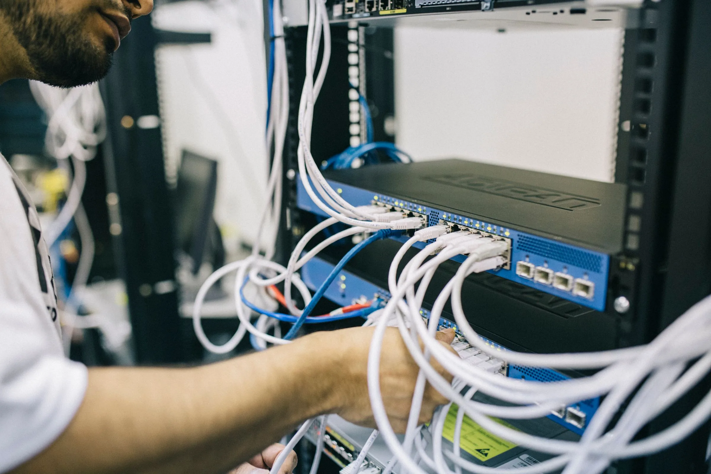 Teknisi merapikan kabel jaringan di rak server