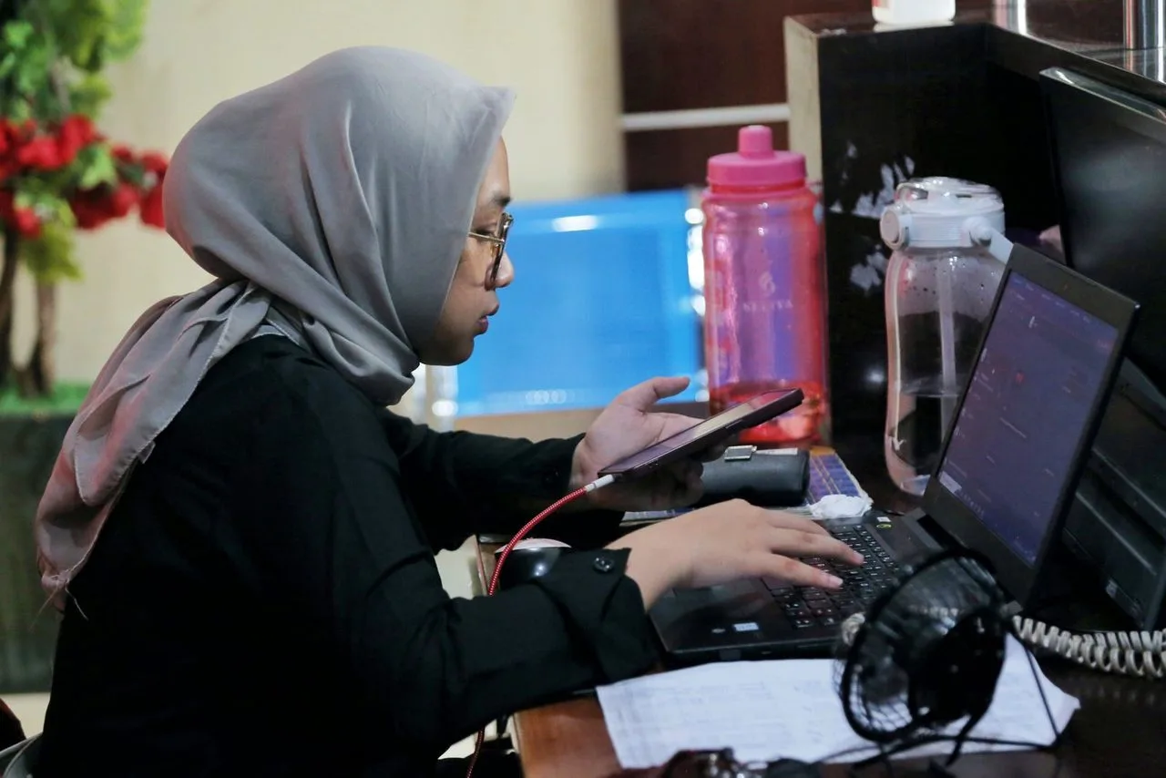 Peserta berhijab bekerja dengan komputer di meja kantor