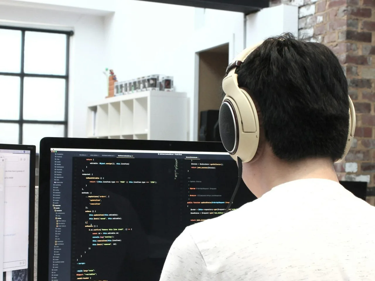 Programmer berheadphone bekerja di depan komputer